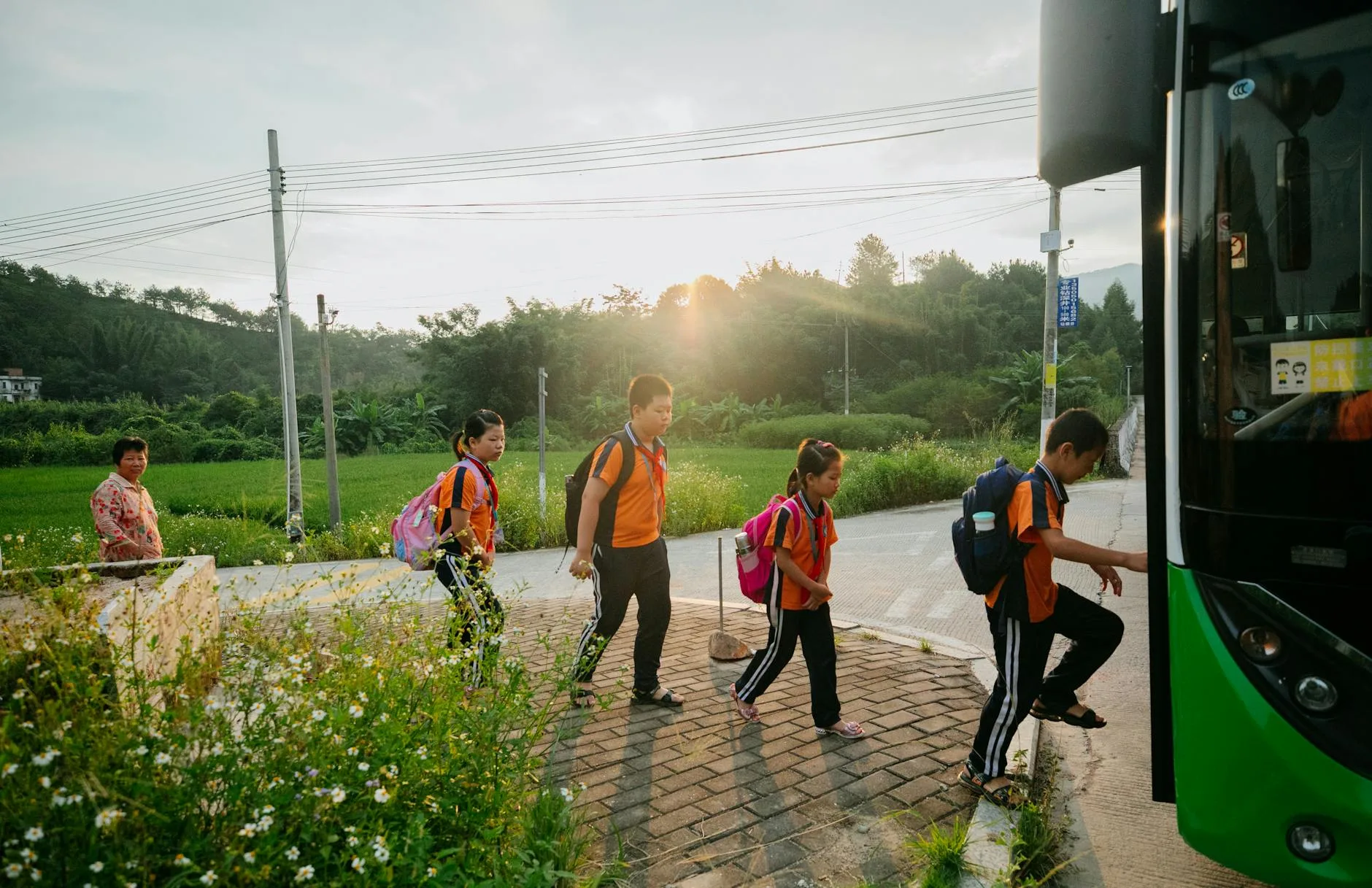 group of teenagers with backpacks boarding a school bus